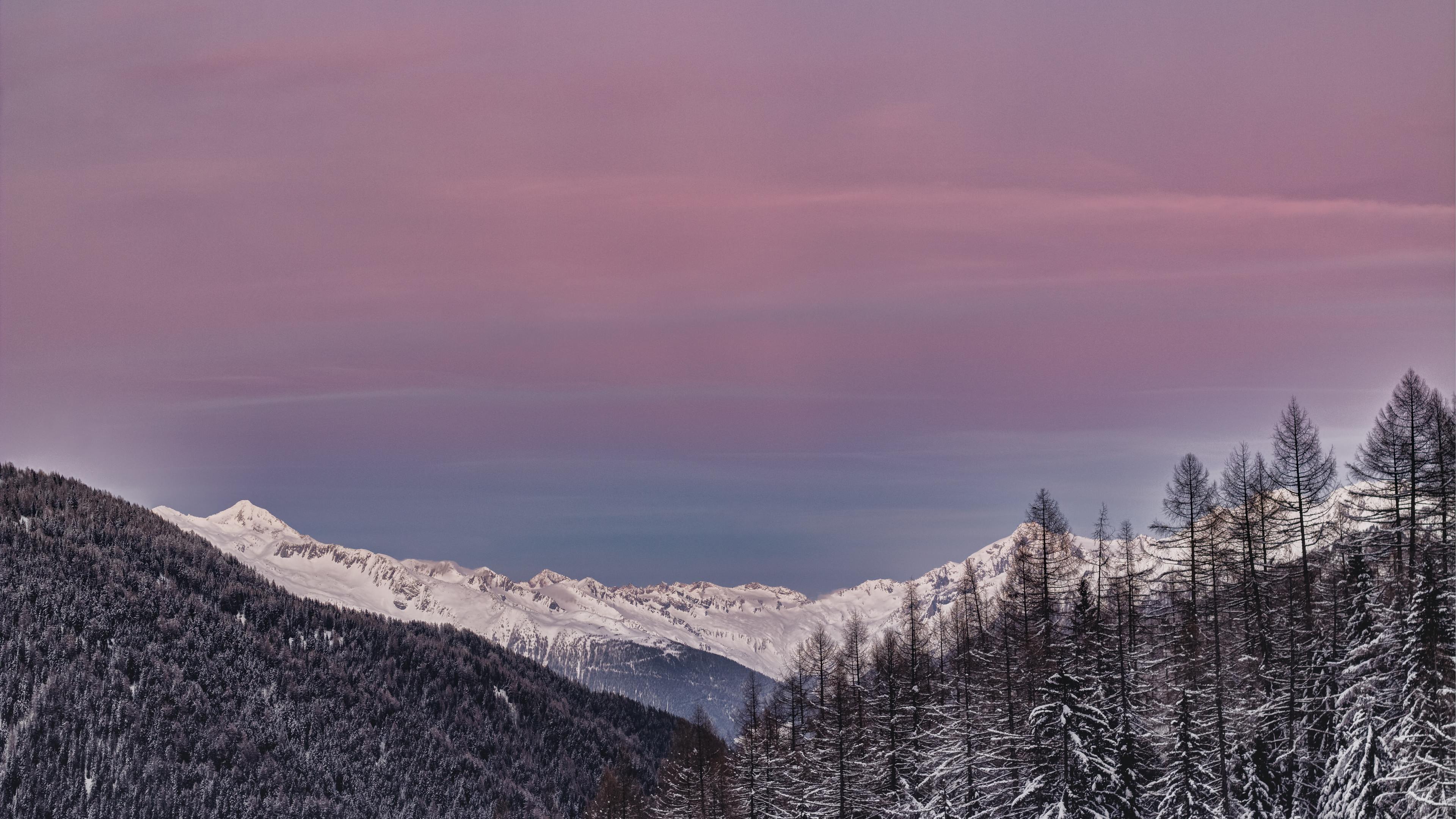 mountains covered with snow and surrounded with trees 4k 1540139309