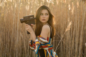 brunette girl in field with camera 1575664956