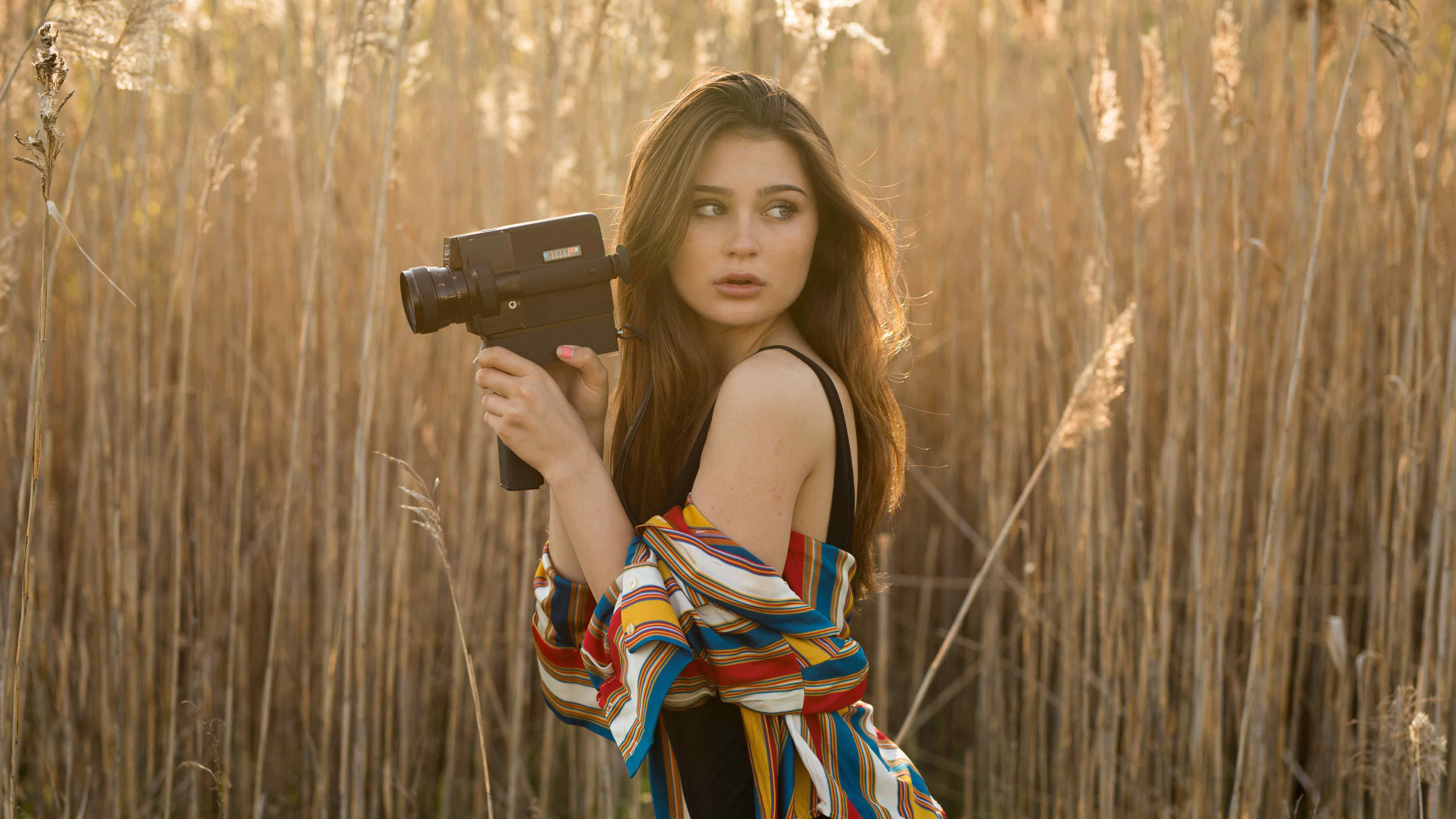 brunette girl in field with camera 1575664956