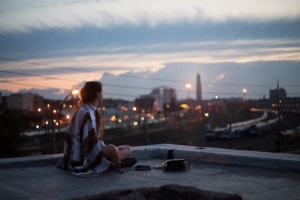 girl sitting on rooftop looking towards town 1575665237